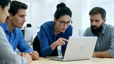 Equipo de profesionales en una oficina analizando datos de una estrategia de contenidos SEO en la pantalla de un ordenador portátil.